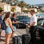 Service de Taxi Saint-Tropez avec des chauffeurs aidant les touristes à un stand fréquenté sous le soleil à Saint-Tropez.